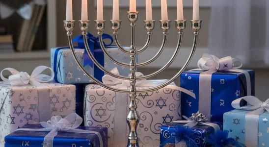 Menorah lit with candles surrounded by festive Hanukkah gifts and decorations